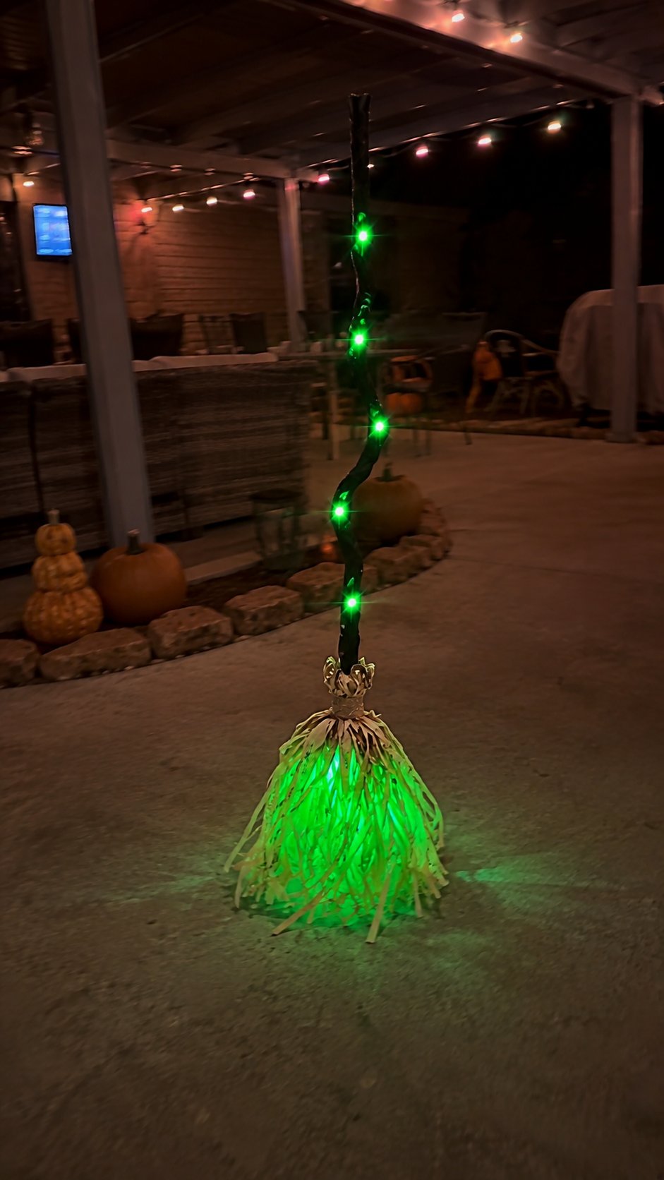 Customer-style photo of the glowing Halloween broom on a covered backyard patio